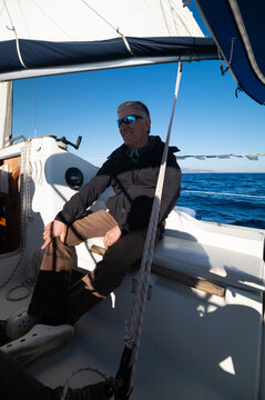 Mature man enjoying a sunny day sailing on sailboat