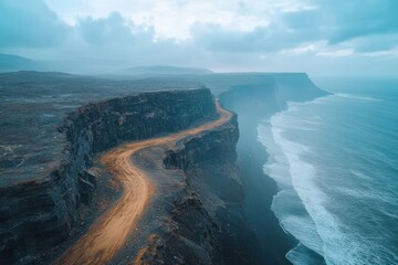 Scenic coastal road winding along dramatic cliffs by the ocean under a cloudy sky at dawn