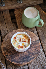 Portion baked eggs with cheese on a board on a wooden table. 