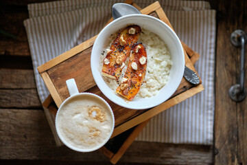 rice cereal with caramelized banana, peanut butter and nuts. wooden background, side view