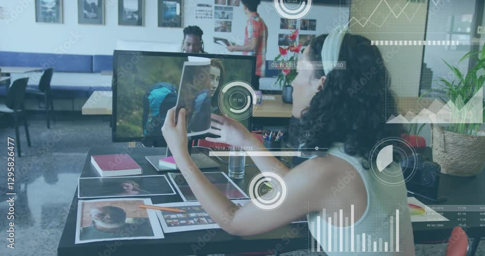 Poster creative team reviewing photographs with data processing animation overlay in office