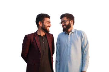 Two young South Asian friends share a warm smile and laughter in a mix of traditional and modern attire isolated on white background.