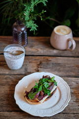 toast with melted cheese, fried bacon, sun-dried plums and parsley. homemade bread. Top view. Wooden background	
