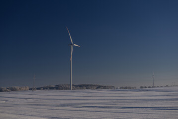 WIND FARM - Turbines in snowy fields against a blue sky
