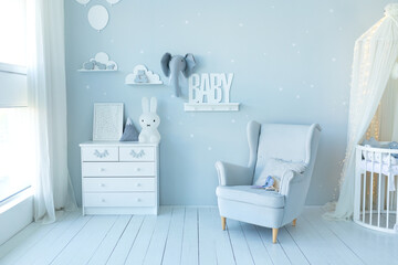 Stylish skandi interior of newborn baby room with bed, grey armchair and wooden dresser with toy and picture. Decor children room with furniture. Crib in a modern nursery room. Baby cot with canopy © stock_studio