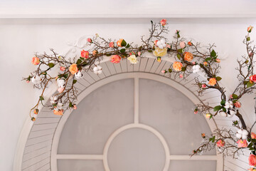 Window and flowers. Yellow and pink rose flowers, bloom and climb on facade arched window at home....