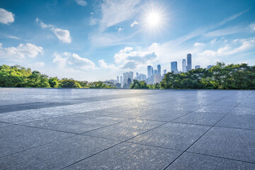 Empty square floor and green forest with city skyline on a sunny day