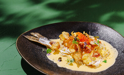 Gourmet fish dish with crispy toppings and vibrant sauce