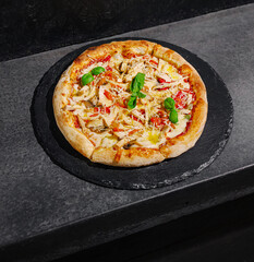 Freshly baked pizza with toppings on a slate board in restaurant