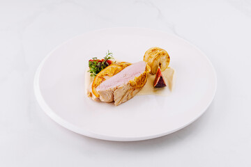 Roasted pork loin with figs and potatoes on a white plate