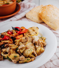 Fried potatoes with mushrooms and grilled vegetables on white plate