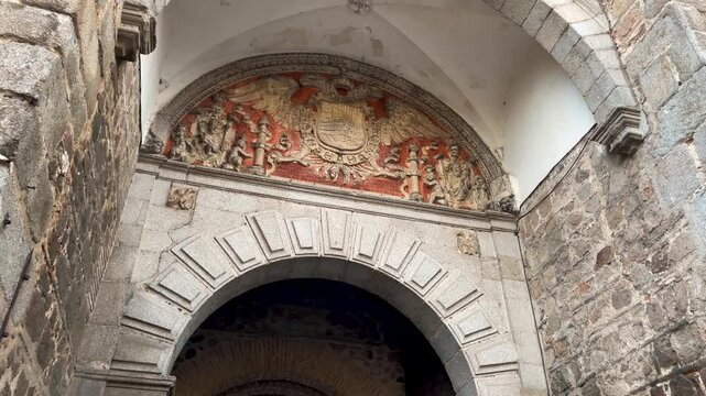 We see the interior door of Cambr&oacute;n where several heraldic elements appear above the arch, the shield with the imperial double-headed eagle, the shield of Philip II, cars appear through the door