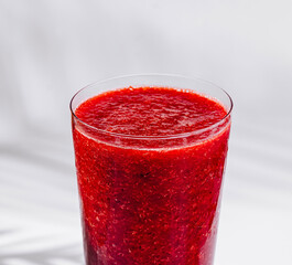 Glass of refreshing cold strawberry smoothie on white background