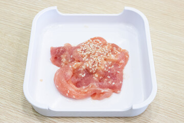 Marinated pork until tender, sprinkled with white flour on a white tray, ready to serve as shabu.
