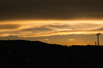 Golden moody clouds by the rays of the dawn sun after sun has just set behind.
