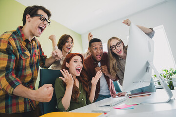 Photo of group five young corporate workers look computer screen raise fists workstation office...