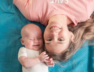 Mother and baby share a joyful moment lying on a blue blanket in a cozy indoor setting