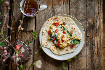 flatbread with fried egg, spinach, hot pepper and zucchini. Wooden background, side view	
