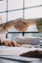 Businesswoman shaking hands with businessman at desk in office