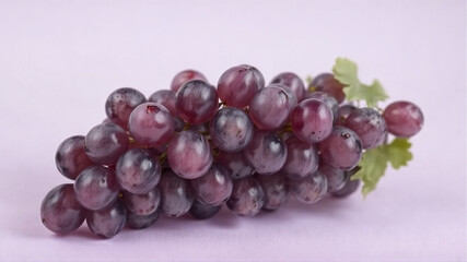 Fototapeta premium A bunch of grapes lies on a light purple background.