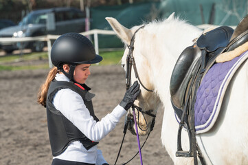 Young equestrian girl petting her horse before riding at an equestrian center