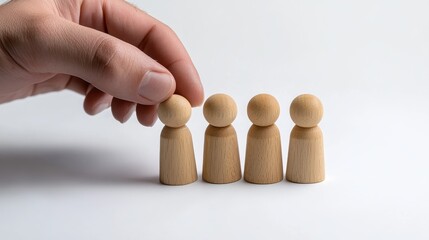 Hand manipulating wooden figurines to create diverse group dynamics on white background