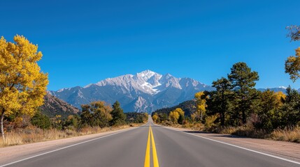 A scenic paved road leading to distant snow capped mountains