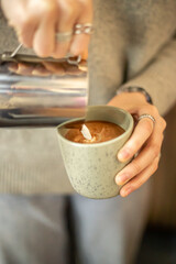 Barista pouring milk for latte art. Barista's hands preparing coffee close-up.