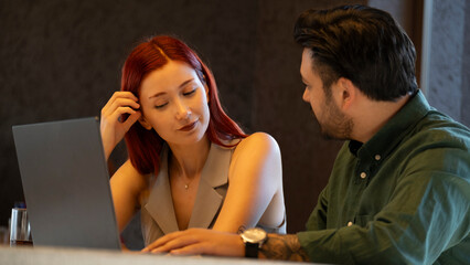 A middle-aged businessman and a young businesswoman are having a tense business meeting with their...