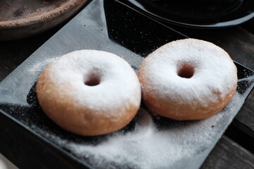 Fresh donuts sprinkled with powdered sugar, perfect for breakfast or a sweet snack.