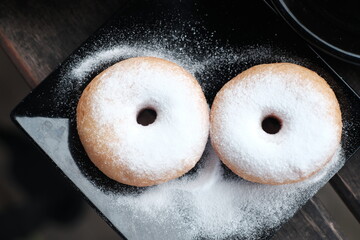 Fresh donuts sprinkled with powdered sugar, perfect for breakfast or a sweet snack.