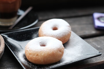 Fresh donuts sprinkled with powdered sugar, perfect for breakfast or a sweet snack.