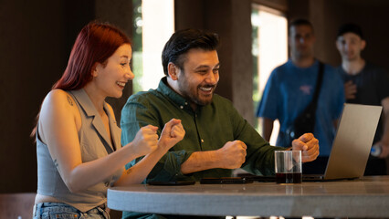 Middle-aged businessman and young businesswoman celebrating enthusiastically during a meeting with...