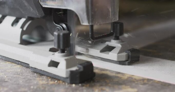 Jigsaw cutting wood plank, close up view of blade in action