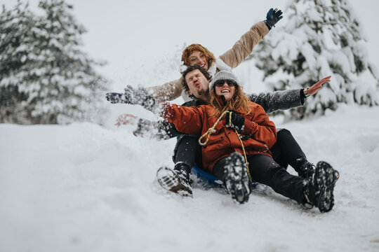 Three friends enjoy sledding together down a snowy slope, showcasing the joys of winter fun and outdoor adventure in the cold season. Laughter and excitement fill the wintry atmosphere.