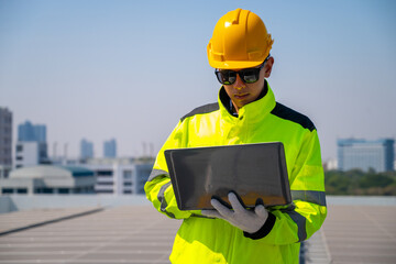 The technician Inspecting Solar Panels on a Factory Roof. An engineer wearing safety gear...