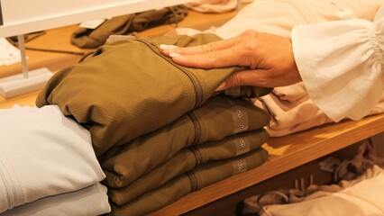 Obraz premium Shopper browsing clothing selection in boutique feeling fabric texture Decision-making process influenced by quality style and modern fashion trends in premium retail environment Shopping concept