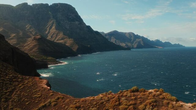Drone shot capturing mountains and hills with continuos tides in ocean water on Gran Canaria at Canary Islands, Spain.