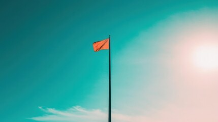 Vibrant Red Flag Against a Clear Blue Sky with Sunlight Radiance