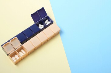 Organization of weekly medication in a multi-compartment pill organizer on a pastel background