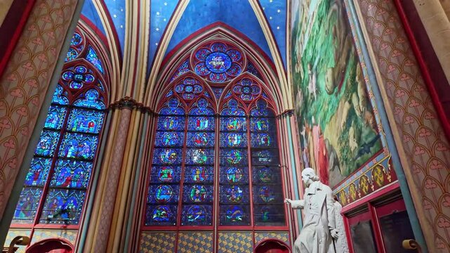 Stunning stained-glass interior of a historic Notre Dame cathedral with high vaulted ceilings and murals, Paris, France.