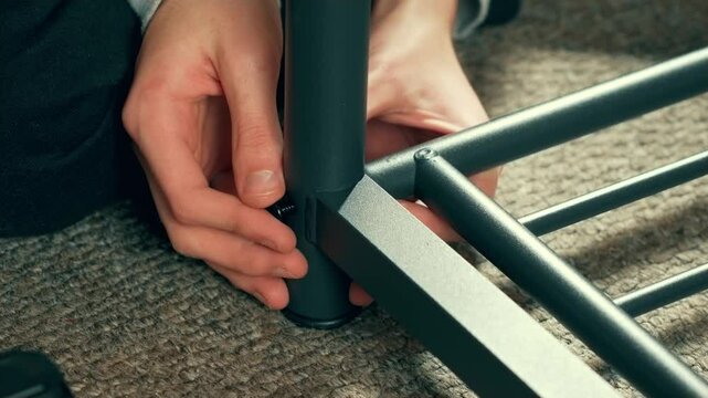 Man piecing together furniture, tweak table or fasten wardrobe, using screwdriver. Craftsman hands fastening home components. Performing fixing or optimization tasks