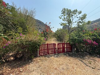barrière de bois peinte en rouge délimitant un terrain dans la campagne thaïlandaise