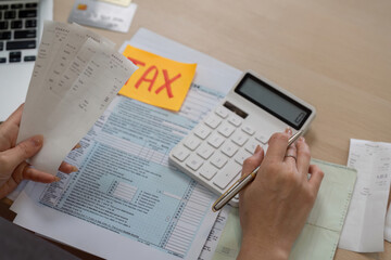 Woman calculating taxes with receipts and a calculator for financial management.