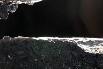 Ice crystals freezing on a black background, abstract winter photo surface