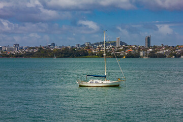 A sailboat moored in Auckland Harbour with the vibrant Auckland CBD skyline in the background....