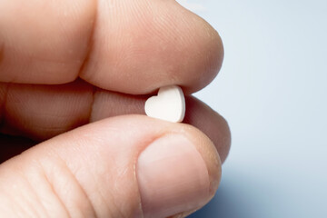 medical concept, heart shaped pill in a man's hand.