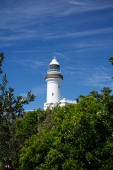 Byron Bay lighthouse with blue sky and green trees 