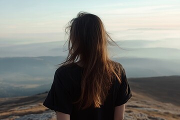 Fototapeta premium A woman standing on top of a mountain and looking at the endless horizon. 