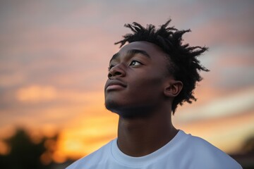 A young man against the backdrop of a sunset, with an expression full of determination and hope for new opportunities.
